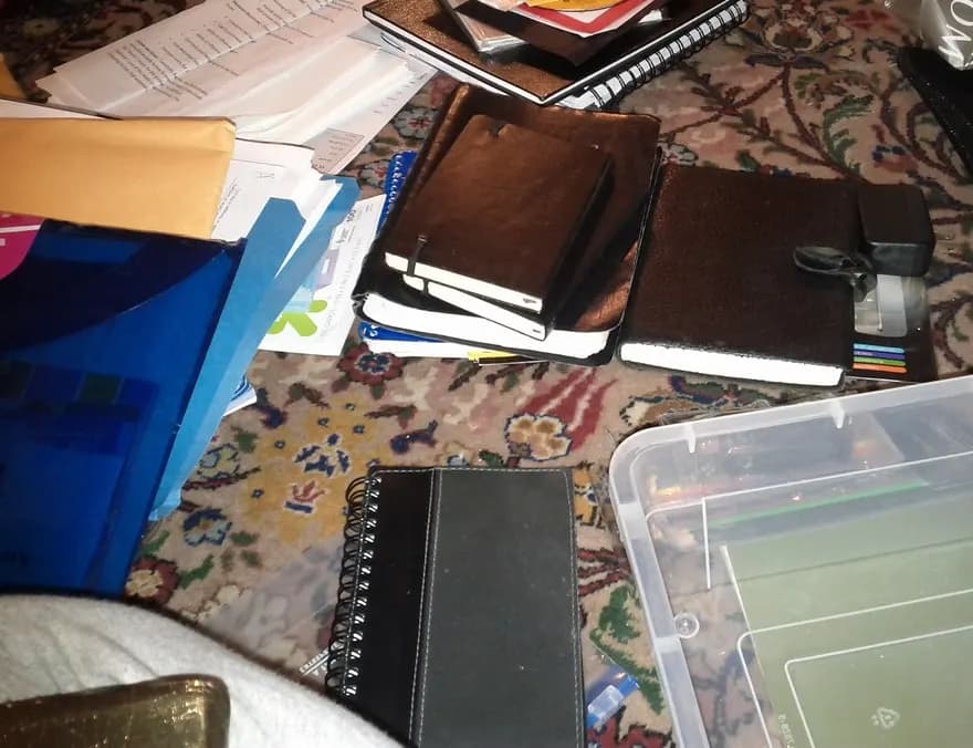 Unsorted folders, receipt books, notebooks and loose paperwork spread across a floor next to an empty storage box