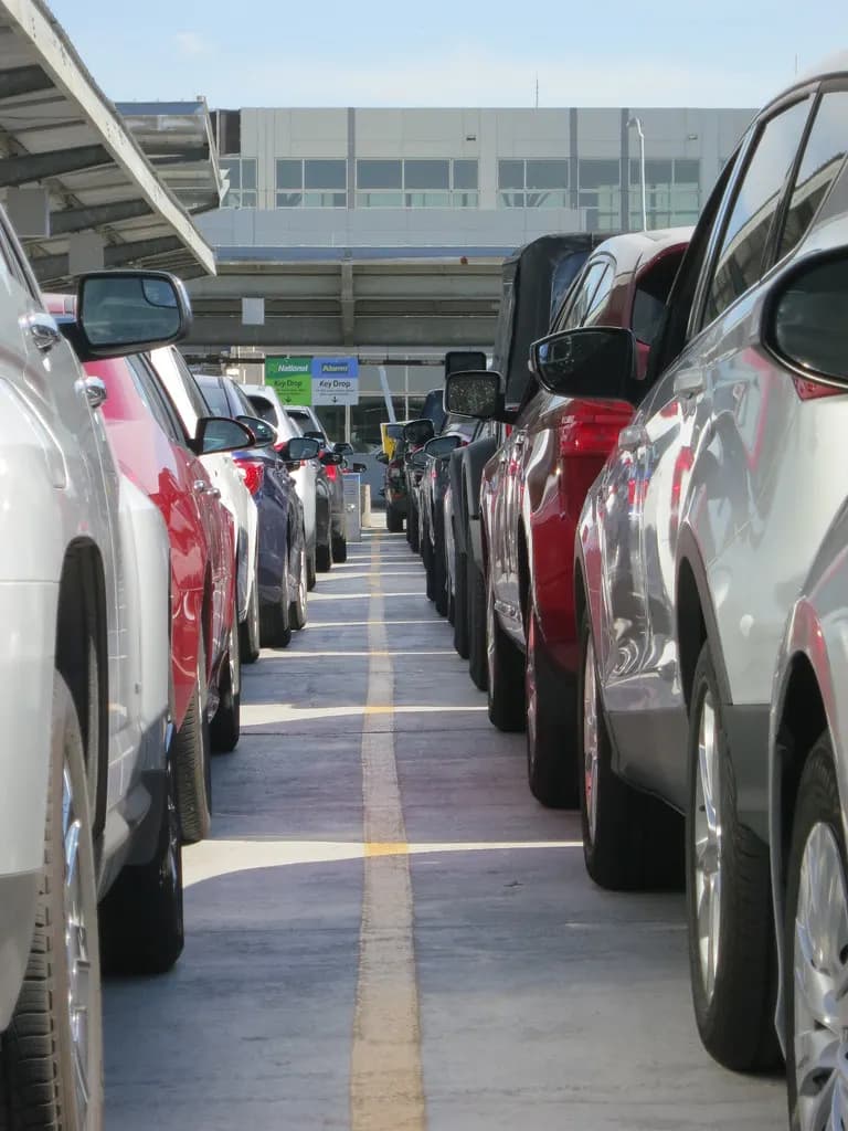 Two long rows of returned rental cars parked in an airport rental car garage