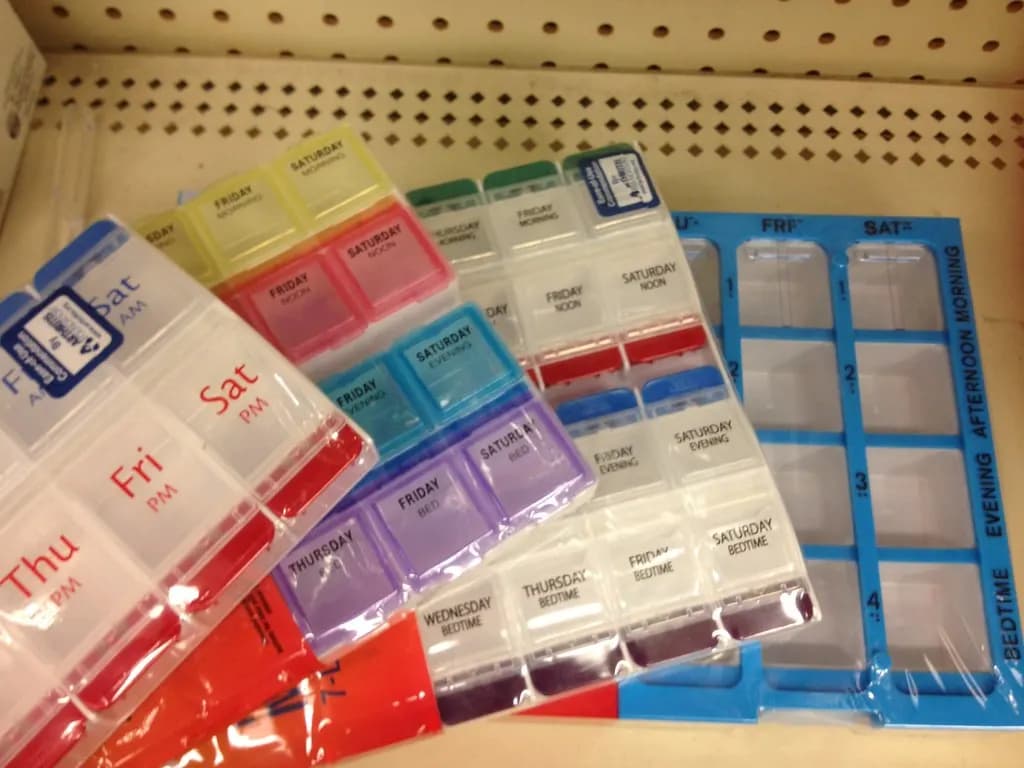 Several large weekly pill organizers with labelled day and time compartments
