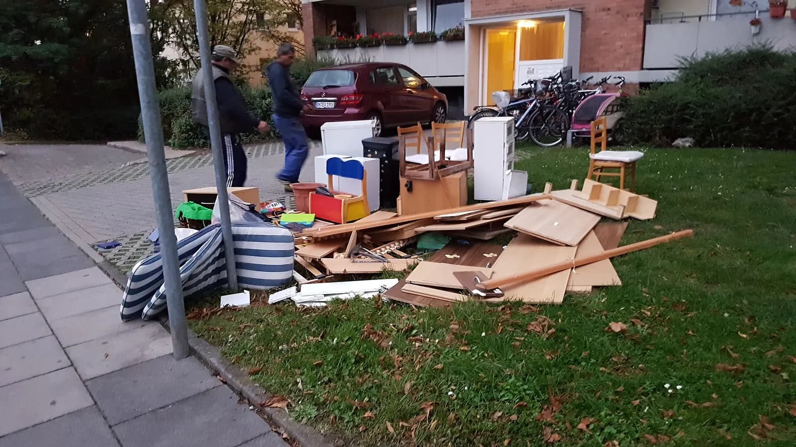 Discarded wardrobes, cabinet panels, a mattress and chairs piled at a curb for bulky-item collection
