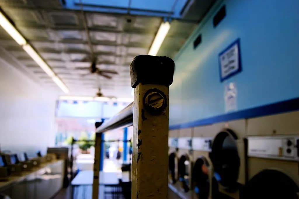 Interior of a self-service laundromat with rows of washers along the wall and a folding table in the center