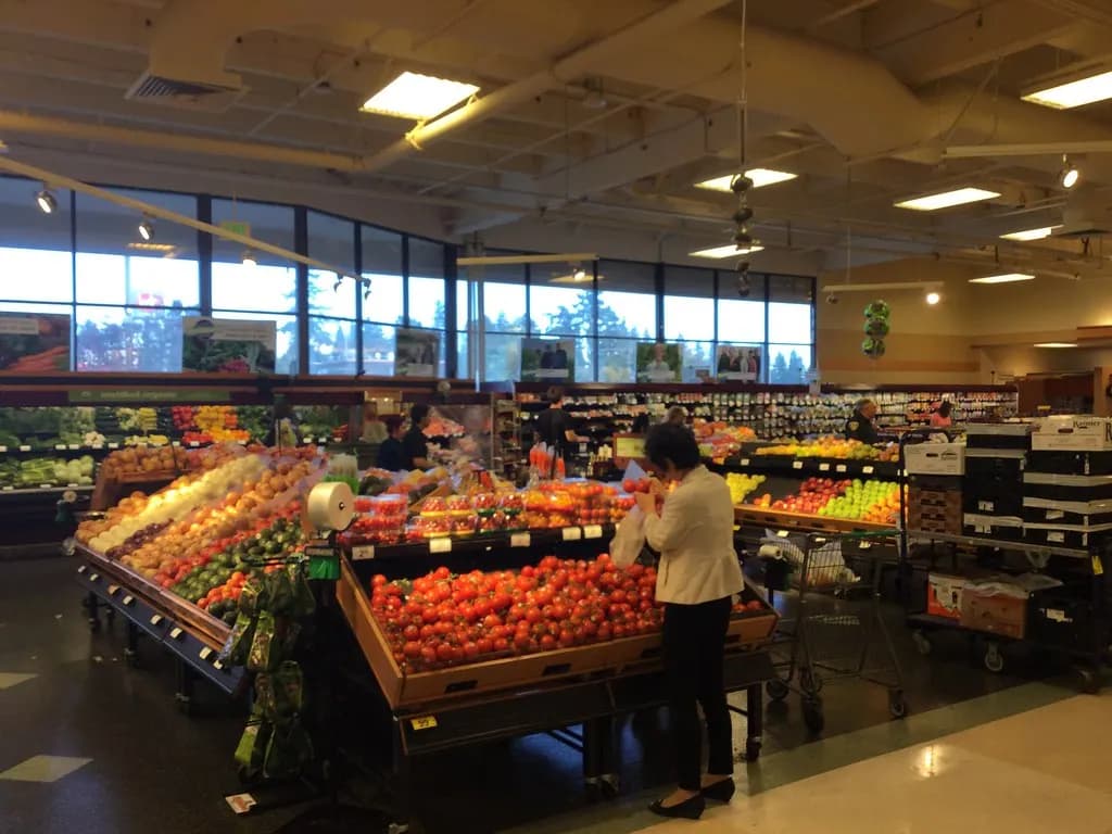 Supermarket produce section with tomatoes, apples and other fresh fruit and vegetables on display