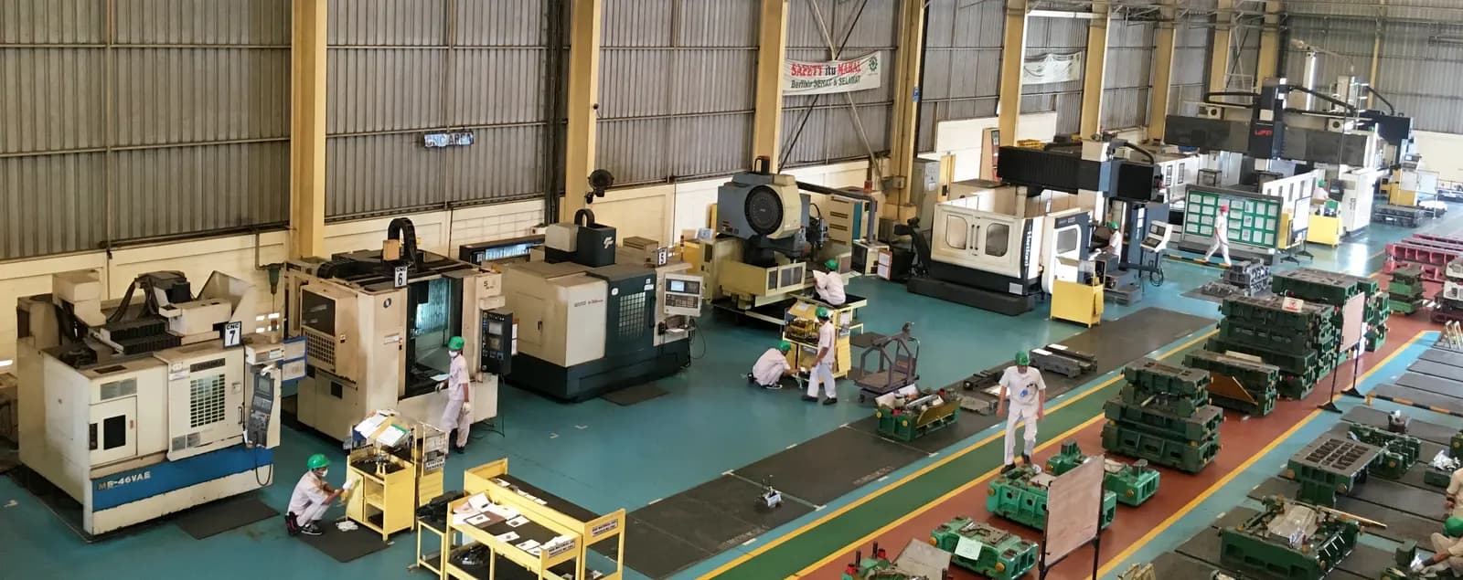 Wide view of a machine shop floor with rows of CNC machining centers and workbenches