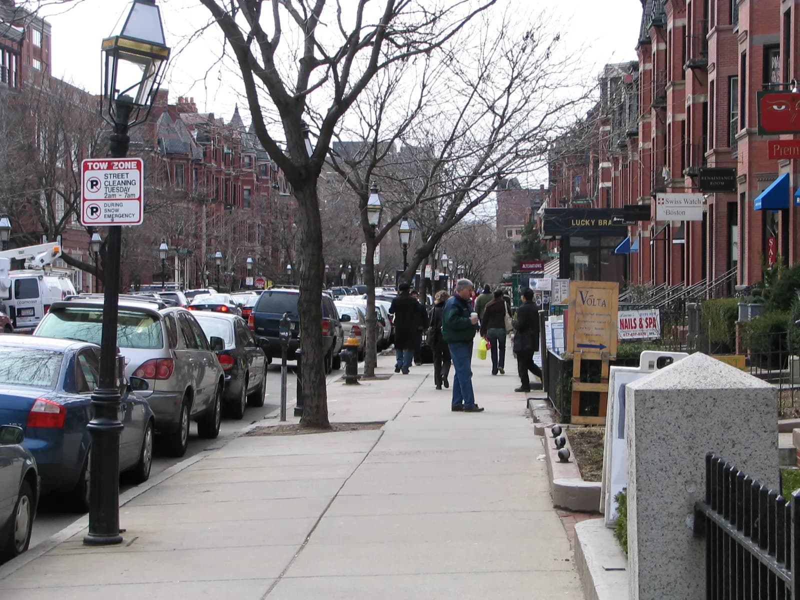 Shoppers on a sidewalk lined with brownstone storefronts on Newbury Street in Boston's Back Bay