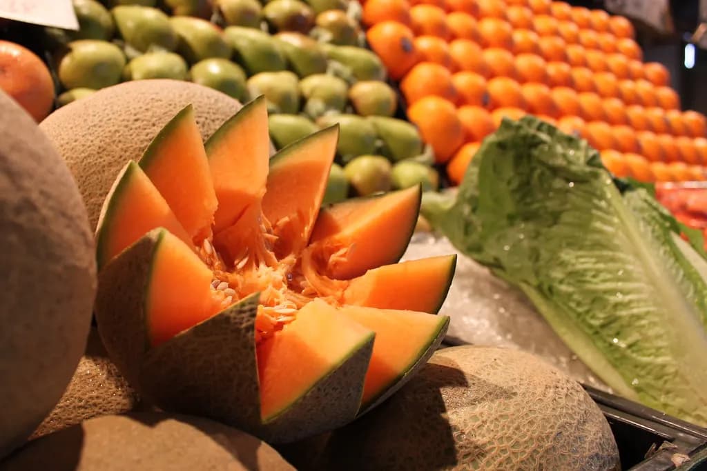 A cut cantaloupe, oranges and lettuce on a produce stand at Soulard Market in St. Louis