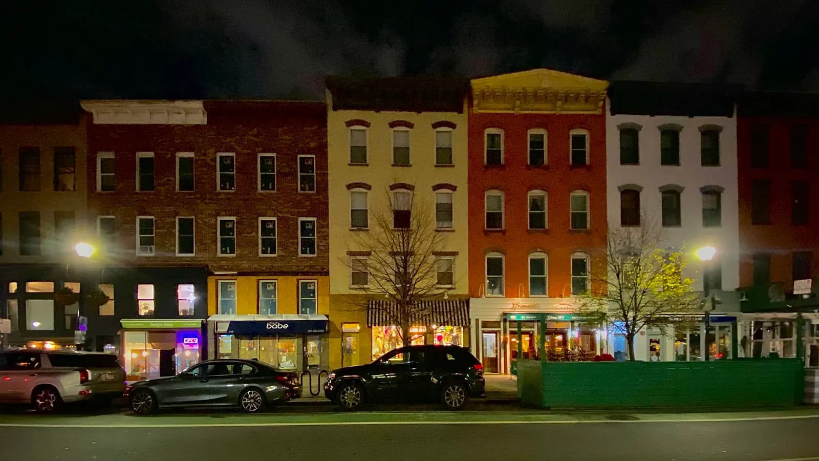 Washington Street in Hoboken, New Jersey at night, with lit ground-floor shops below brick rowhouses