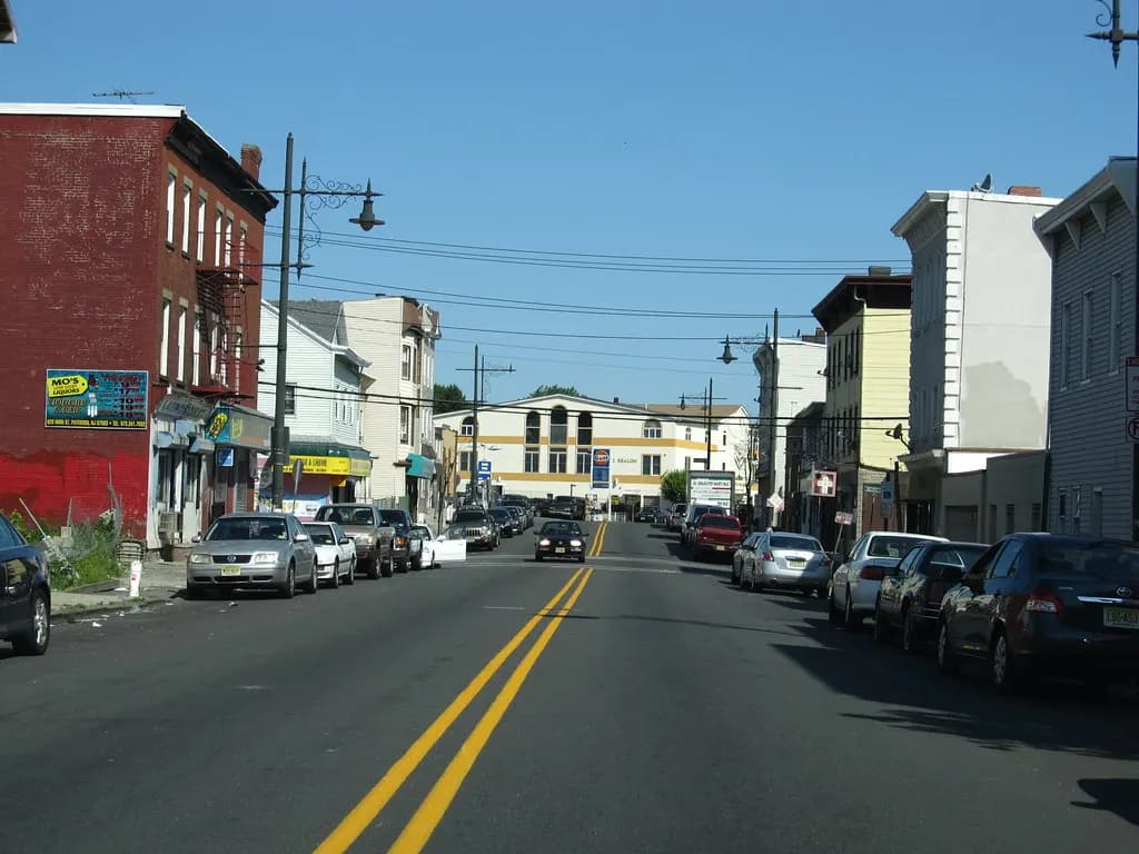 Main Street in Paterson, New Jersey, lined with small shops and parked cars