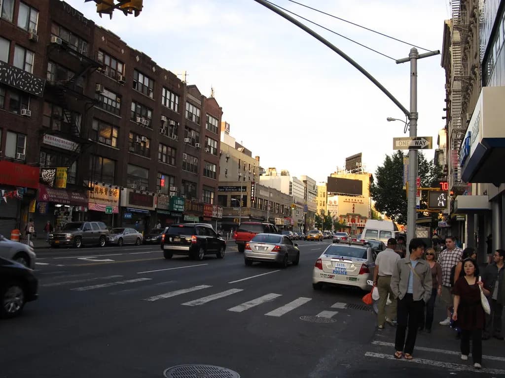 Canal Street in Manhattan's Chinatown lined with ground-floor shops and pedestrians on the sidewalk
