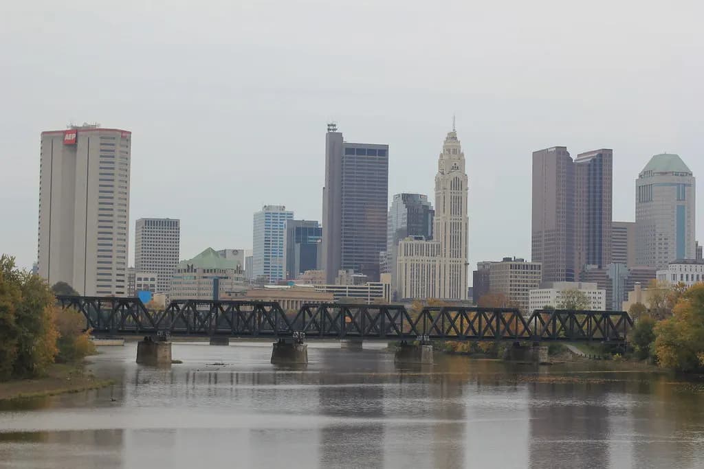 The downtown Columbus, Ohio skyline behind a railroad bridge over the Scioto River