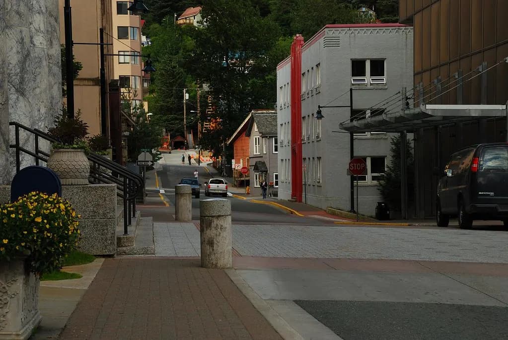 A quiet downtown street in Juneau, Alaska, with brick sidewalks, bollards and wooden houses on the hillside