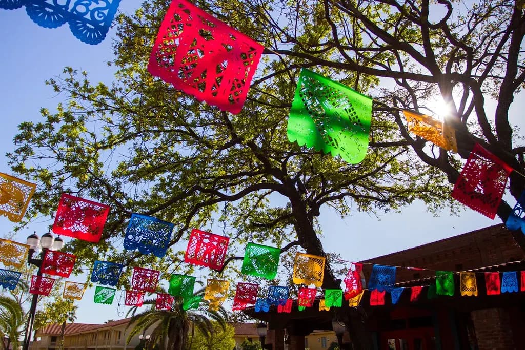 Colorful papel picado banners strung between trees over Market Square in San Antonio, Texas