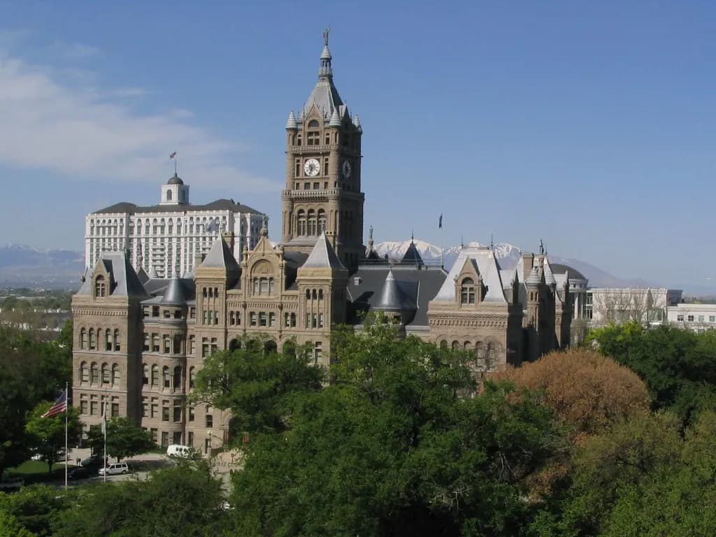 The Salt Lake City and County Building, a sandstone Romanesque building with a central clock tower, surrounded by trees