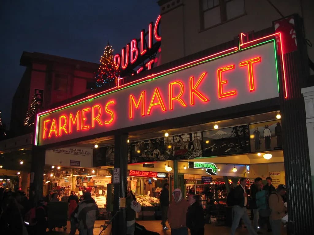 The lit Public Market Center and Farmers Market signs at Pike Place Market, Seattle, in the evening